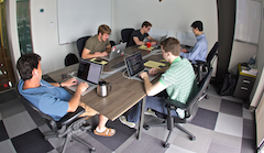 Rustici interns sat at a table doing work on their laptops